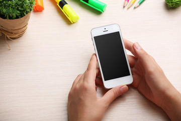 Woman using mobile phone on workplace close up