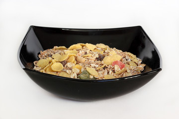 Muesli in black plate on white background