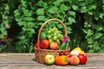 Heap of fresh fruits and vegetables in basket on table outdoors