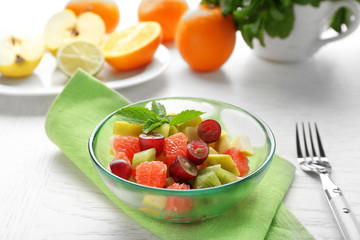 Fruit salad in glass bowl, on light wooden background