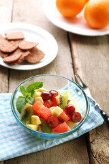 Fruit salad in glass bowl, on  wooden background