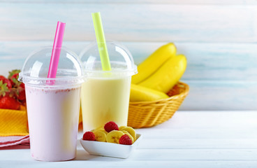 Plastic cup of milkshake on light wooden background