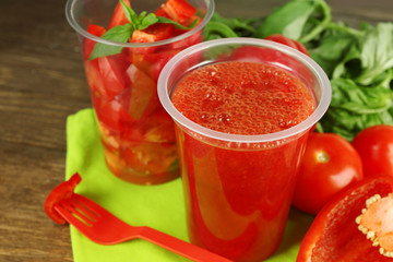 Vegetable and fruit  salad and healthy fresh drink in plastic cups on wooden background. Colorful diet concept