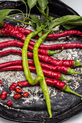Red and two green chili peppers on old plate  