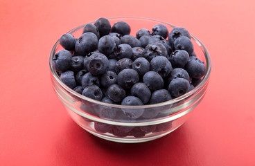 ripe blueberries in bowl isolated on red