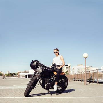 Biker girl sitting on vintage custom motorcycle