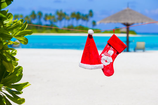 Red Santa hat and Christmas stocking on the beach