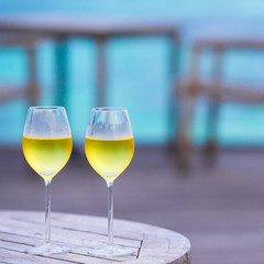 Two glasses of tasty white wine at sunset on wooden table