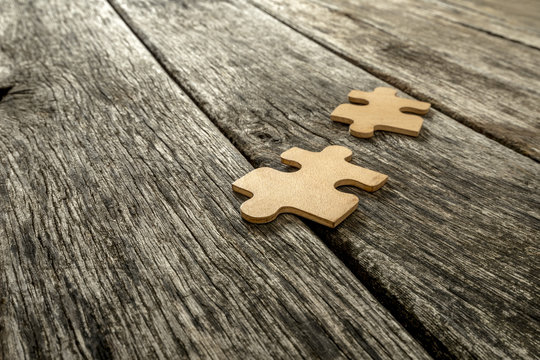 Two puzzle pieces lying on wooden rustic boards