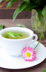 Cup of herbal tea with wild camomiles, mint and flowers