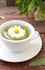 Cup of herbal tea with wild camomiles, mint and flowers