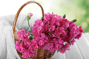 Fototapeta na wymiar Beautiful bouquet of pink carnation in basket on bright background