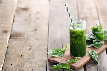 Glass of spinach juice on wooden background