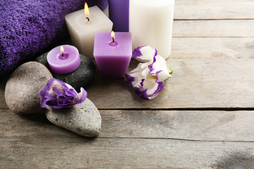 Obraz na płótnie Canvas Spa still life with purple flowers towels, candles and pebbles on wooden background