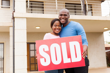 young couple holding sold sign