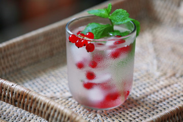 Glass of cold refreshing summer drink with berries and ice cubes on table close up
