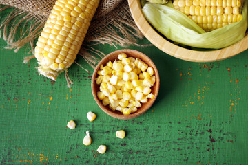 Fresh corn on cobs on green wooden table, top view
