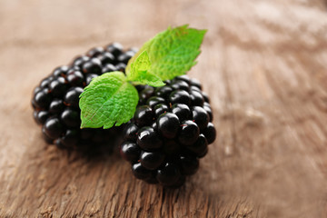 Ripe blackberries with green leaves on wooden background