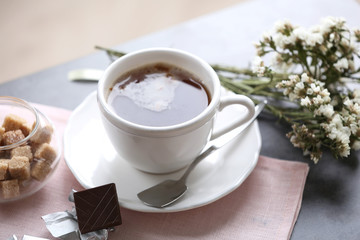 Cup of flavored coffee with chocolate on table with napkin, closeup