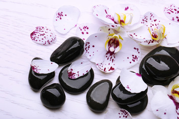 Orchid and zen stones on wooden background close-up