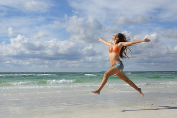 Happy woman jumping on the beach on holidays
