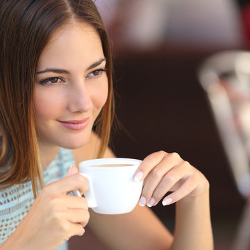 Pensive woman tasting coffee in a restaurant