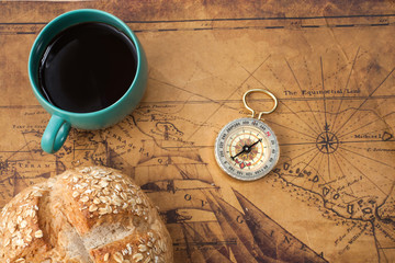 hot coffee cup ,bread and compass on old map