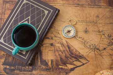 hot coffee cup and compass on old map
