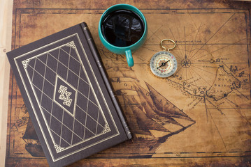 hot coffee cup and compass on old map