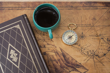 hot coffee cup  and compass on old map