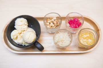 Ice cream served with various topping in small glass on wooden t
