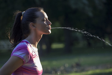 young sporty woman spraying water from her mouth