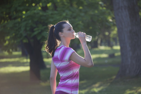 young sporty woman drinks water from a bottle