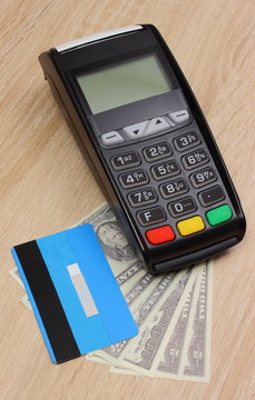 Payment terminal with credit card and money on desk, finance concept