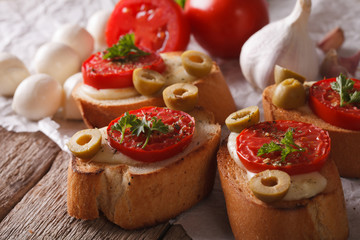 Crostini with baked tomatoes, olives and cheese close-up. Horizontal
