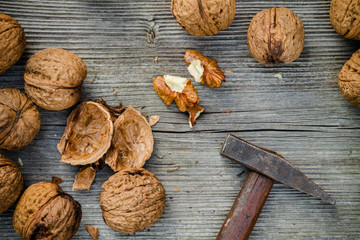 cracked walnuts and hammer on old wooden background