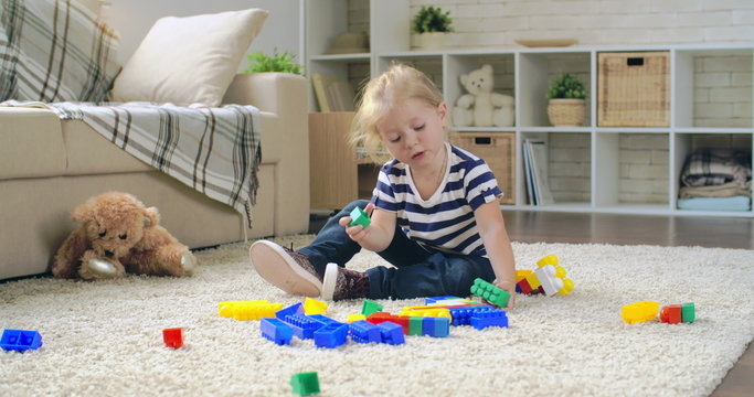Diligent little girl playing meccano in nursery 