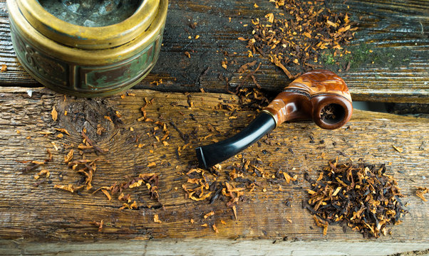 wooden smoking pipe, tobacco and vintage ashtray lie on a wooden table