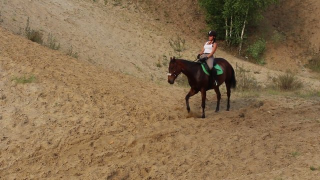 Girl riding a horse on sandy hills