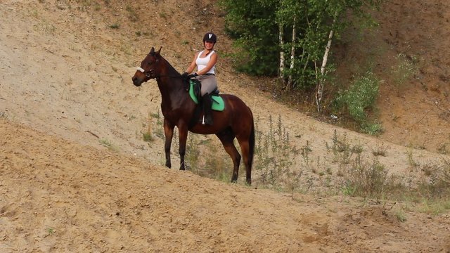 Girl riding a horse on sandy hills