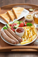 lunch with grilled sausages, French fries, fresh vegetables 