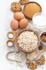 oat flakes and ingredients on a white wooden table, top view