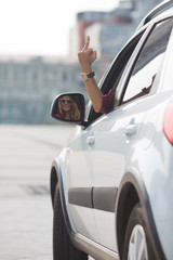 Beautiful lady showing middle finger from her car