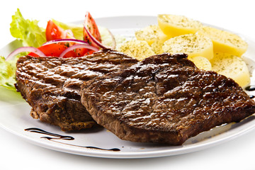 Grilled steaks, boiled potatoes and vegetable salad 