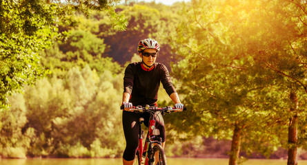 Young woman riding on a bicycle on a countryside road in retro colors.
