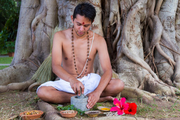 A young man preparing ayurvedic medicine in the traditional manner in India
