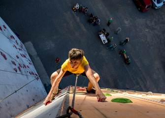 Aged Person Practicing Extreme Sport Elderly Female Climber Makes Hard Move and Looking High Up on Outdoor Climbing Wall Sport Competitions Very Emotional Face Fans Staying on Remote Ground