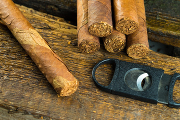 cigar and a knife for cutting lie on a wooden table