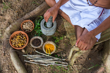 A young man preparing ayurvedic medicine in the traditional manner in India
