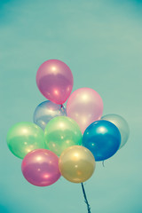 multicolored balloons on blue sky ; vintage color tone.